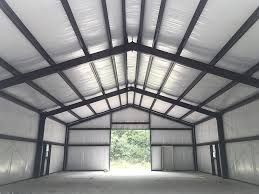 The inside of an empty metal building with a large door open.
