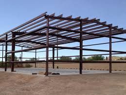 A large metal structure with a roof is being built in the desert.