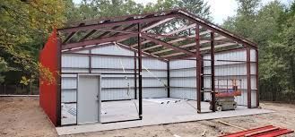 A large metal building is being built in the middle of a dirt field.