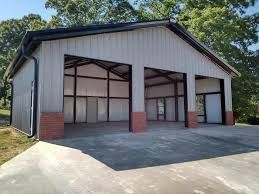 A large metal garage with three doors and a driveway.