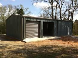 A metal garage with two garage doors is sitting in the middle of a dirt field.