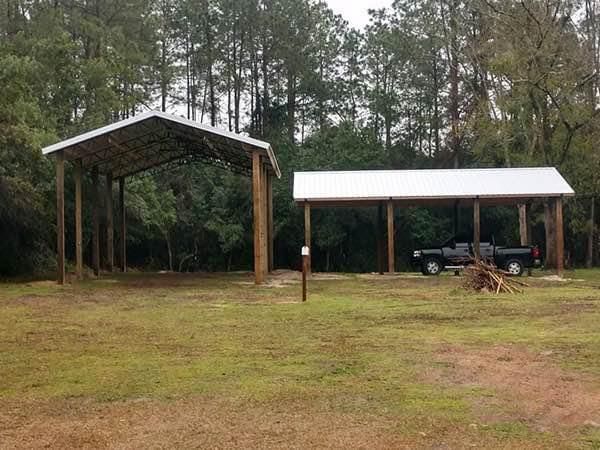 A truck is parked under a covered area in a field.