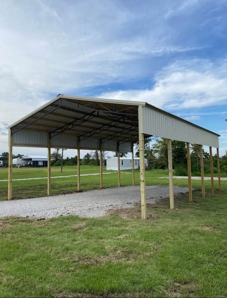 A carport is sitting in the middle of a grassy field.