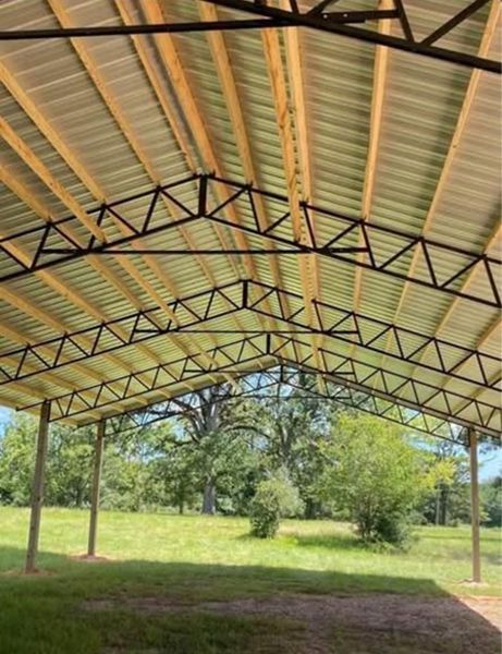 A metal structure with wooden beams is sitting on top of a lush green field.