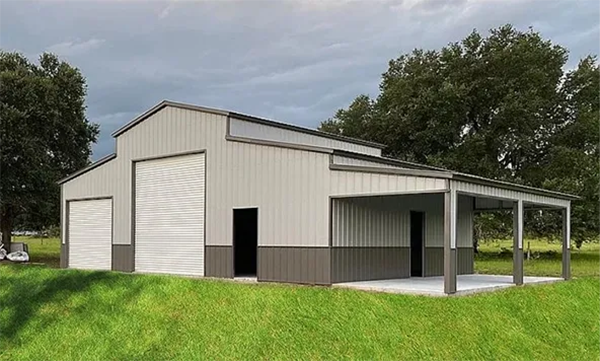 A large metal building with a porch is sitting on top of a lush green field.