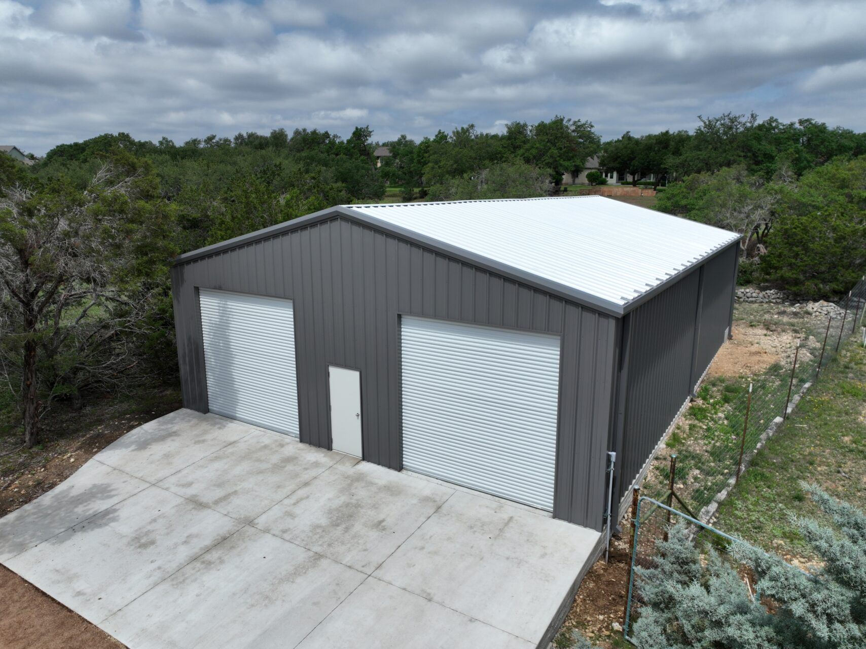 An aerial view of a garage with a white roof surrounded by trees.