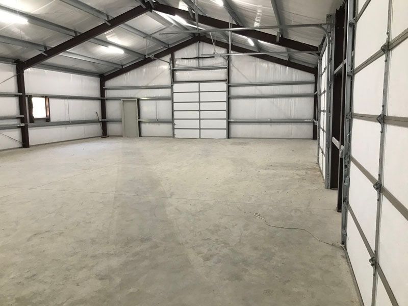 A large empty building with a concrete floor and a garage door.
