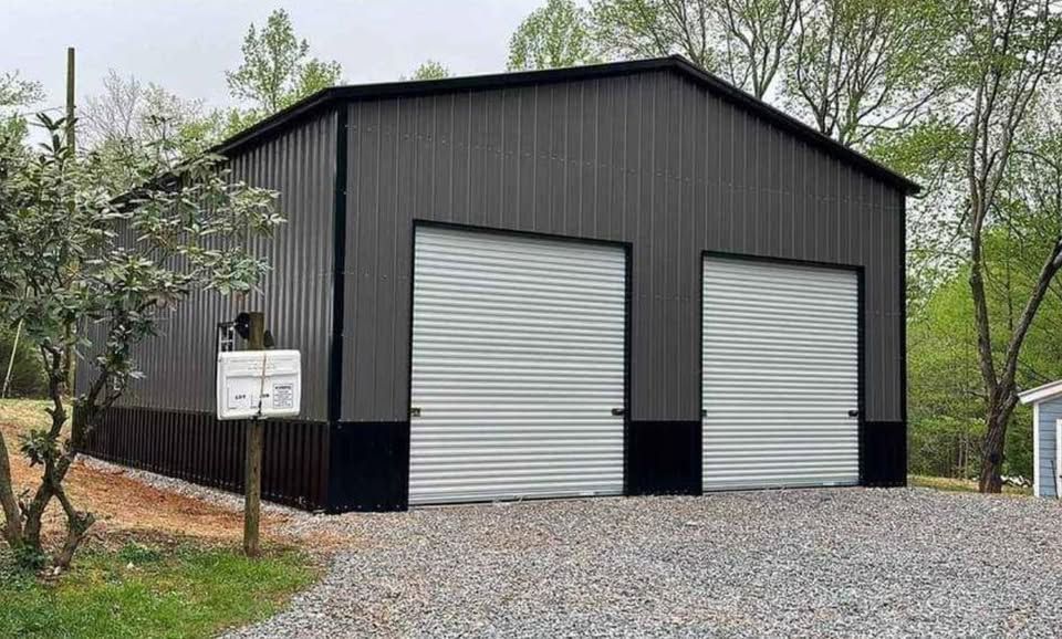 A metal garage with two garage doors and a mailbox in front of it.