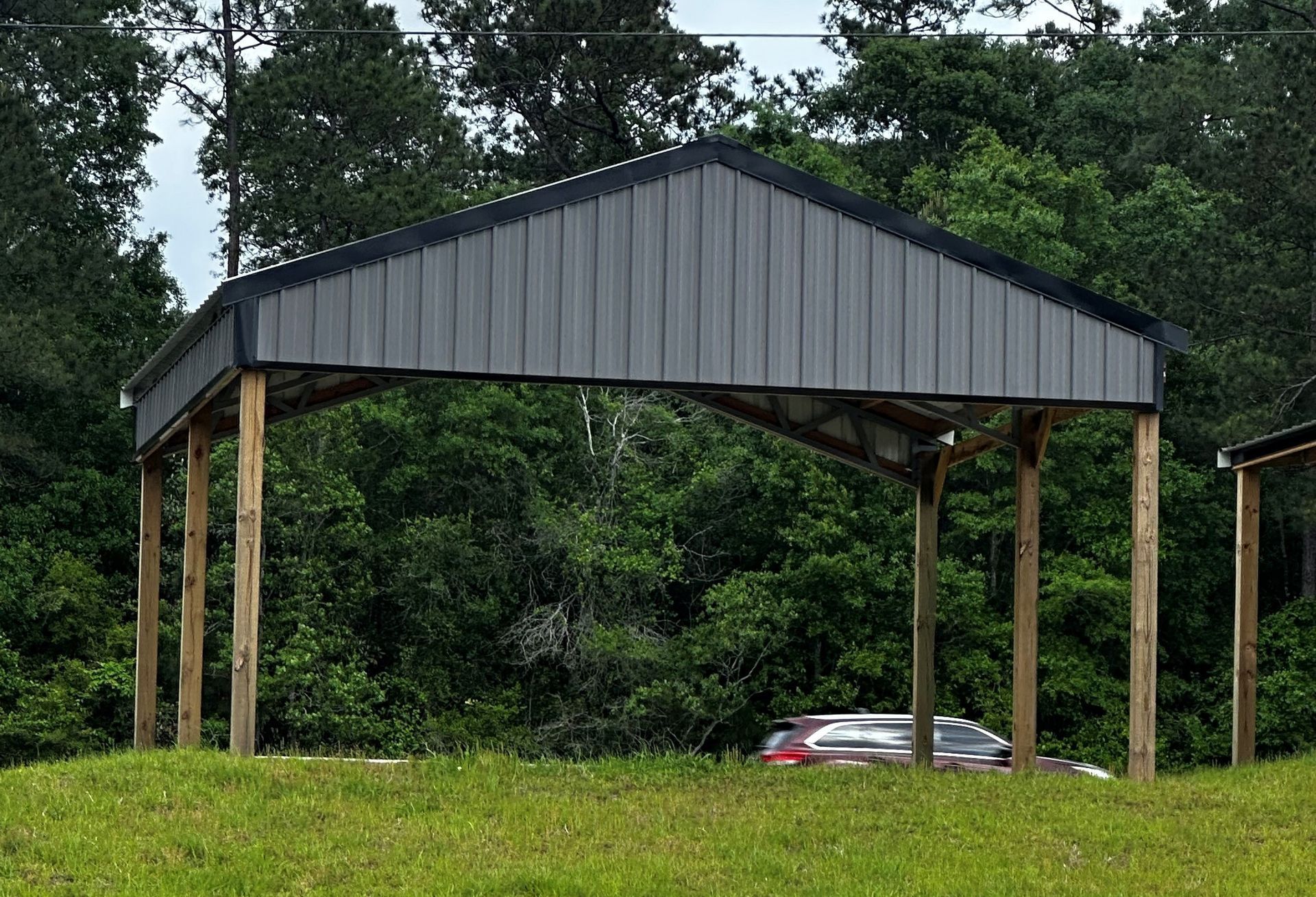 A gray metal-roofed carport with wooden posts