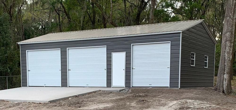 A large metal garage with three garage doors and a door.