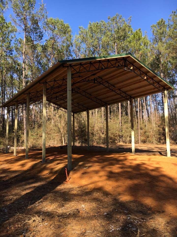 A covered area in the middle of a forest with trees in the background.