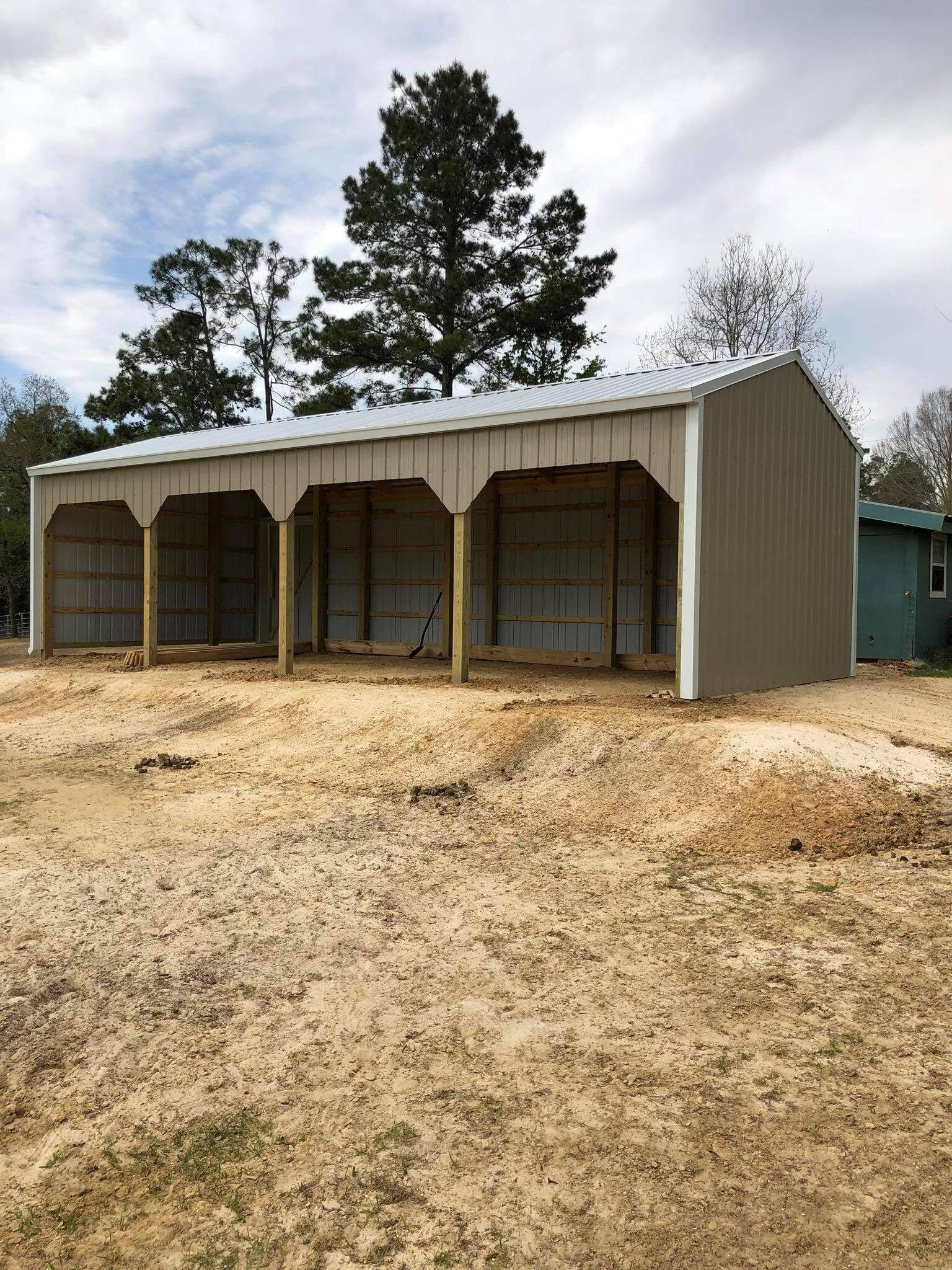 A large metal building is sitting in the middle of a dirt field.