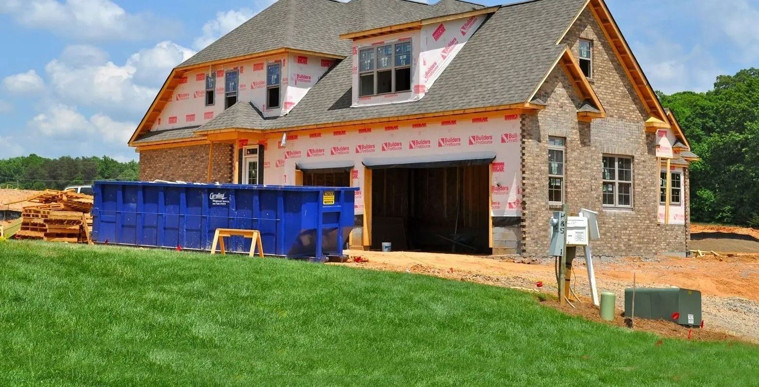 New house under construction with brick exterior, blue dumpster, and green lawn.