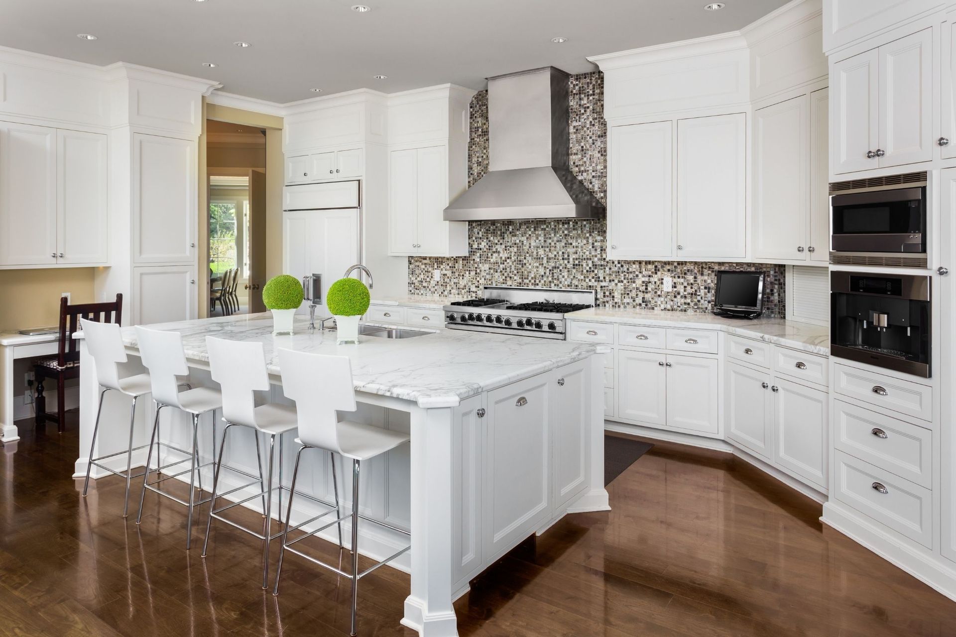 A kitchen with white cabinets and a large island in the middle