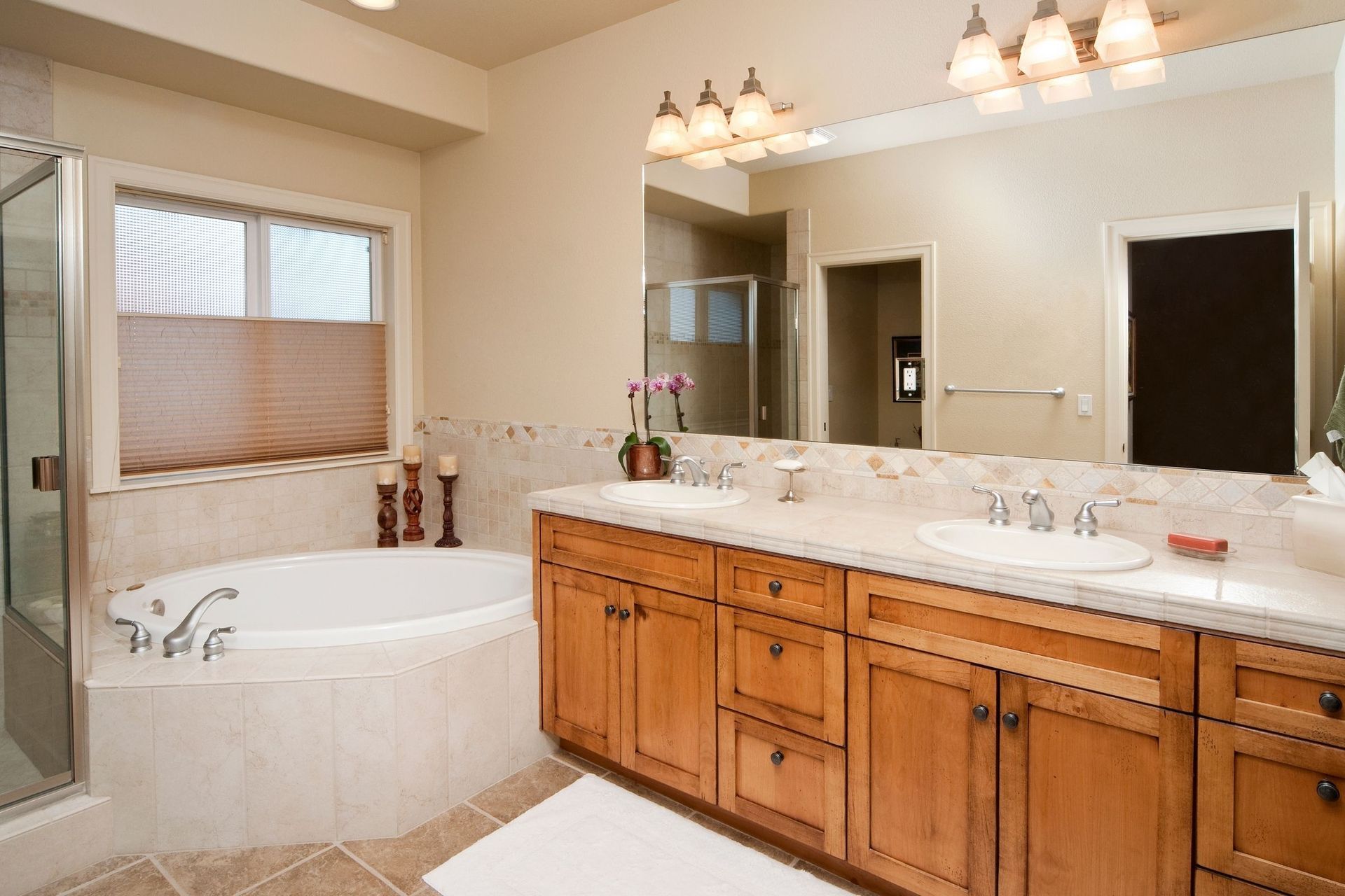 A bathroom with two sinks, a tub, and a large mirror