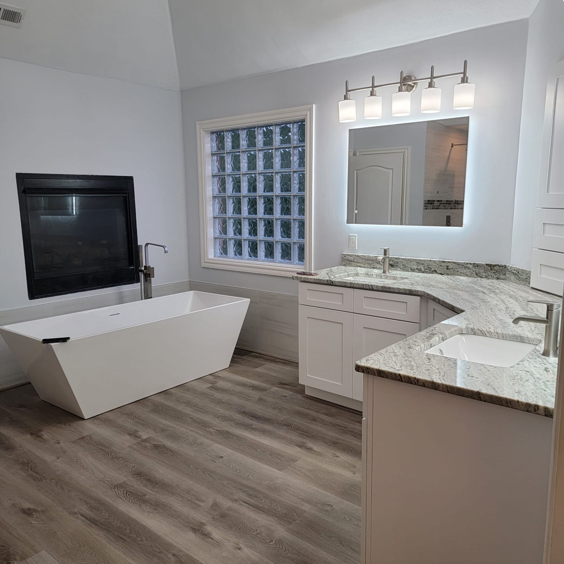 A bathroom with a tub, sink, mirror and fireplace