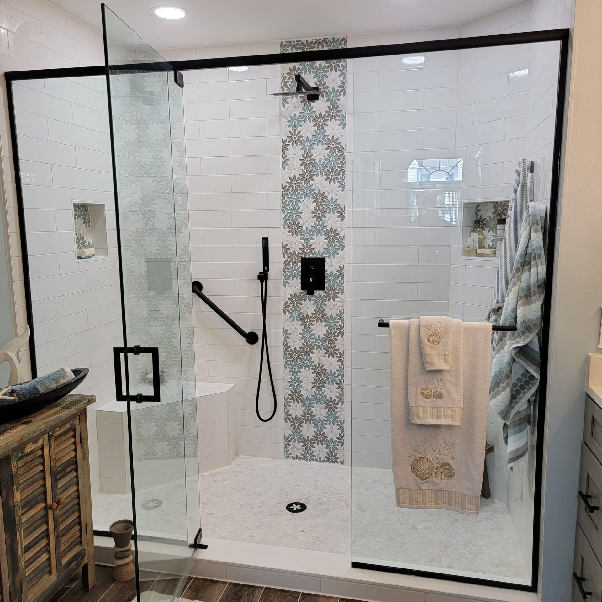 A bathroom with a walk in shower with a glass door