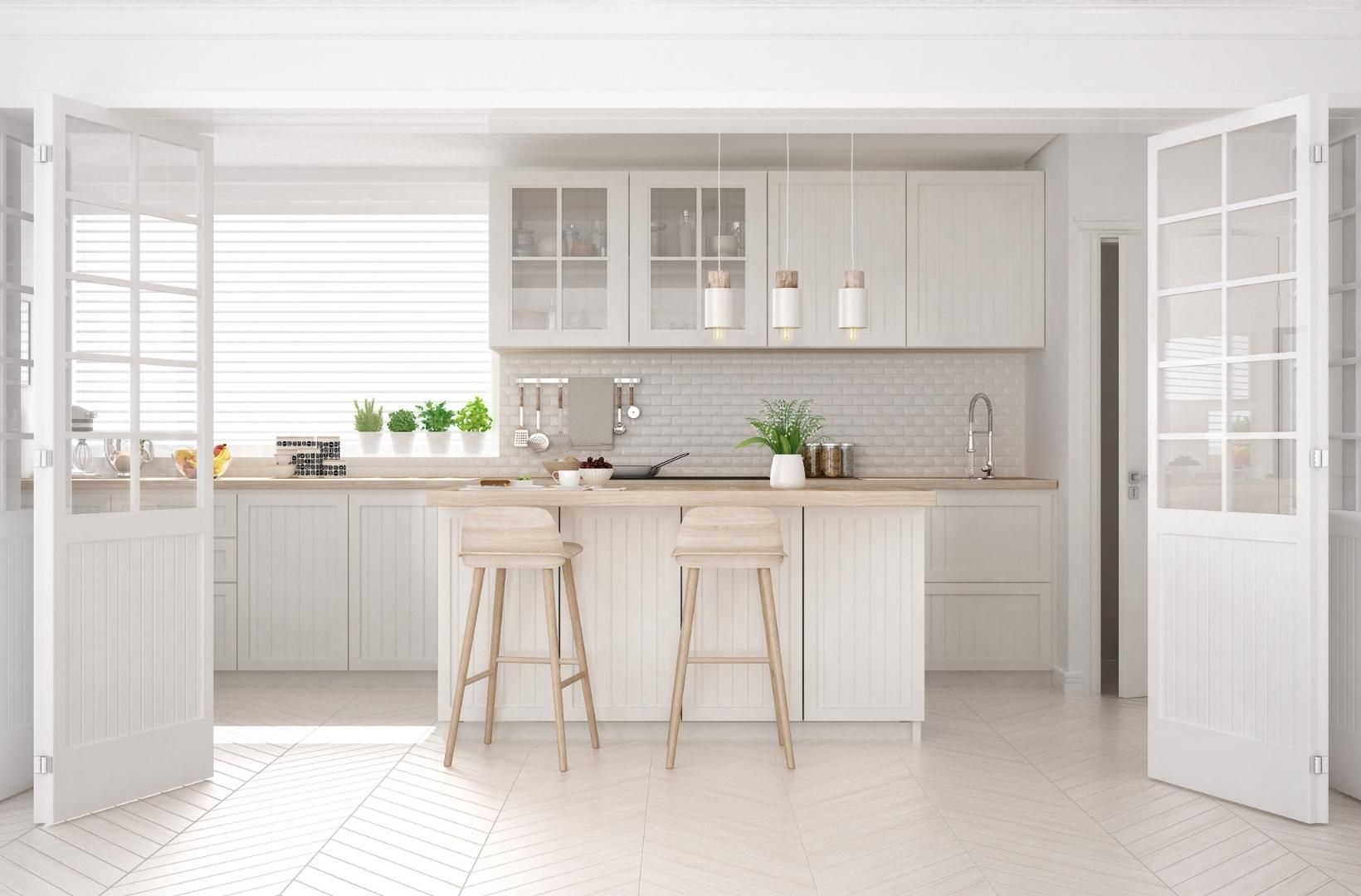 A modern kitchen with white cabinets, stools, and a large island