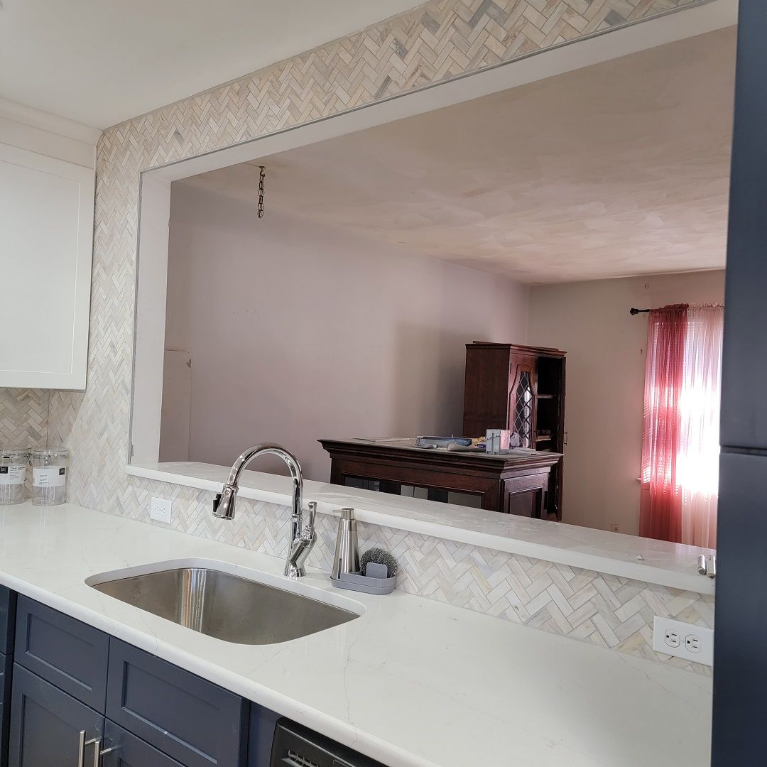A kitchen with a sink and a large mirror on the wall