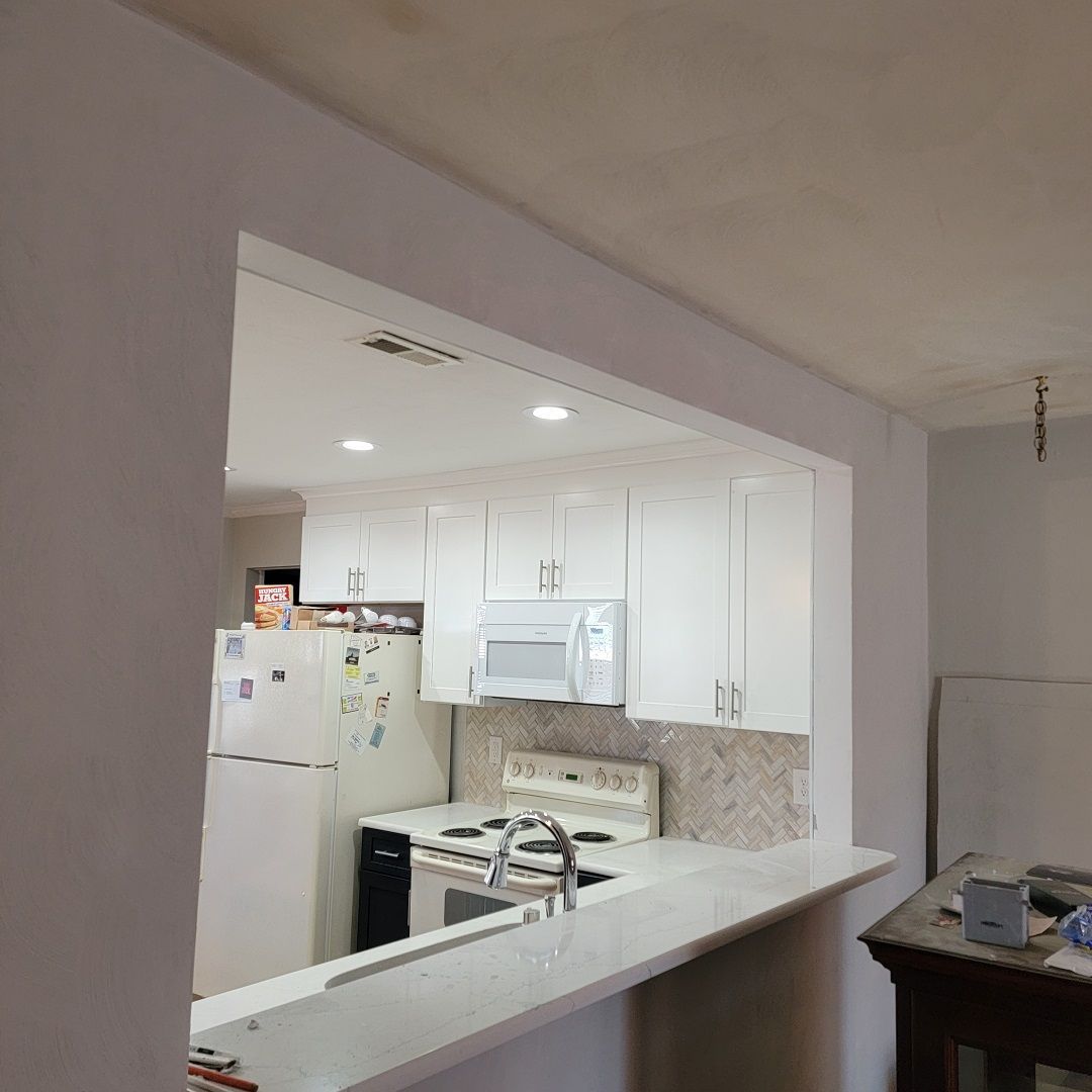 A kitchen with white cabinets, a refrigerator, stove, microwave and sink