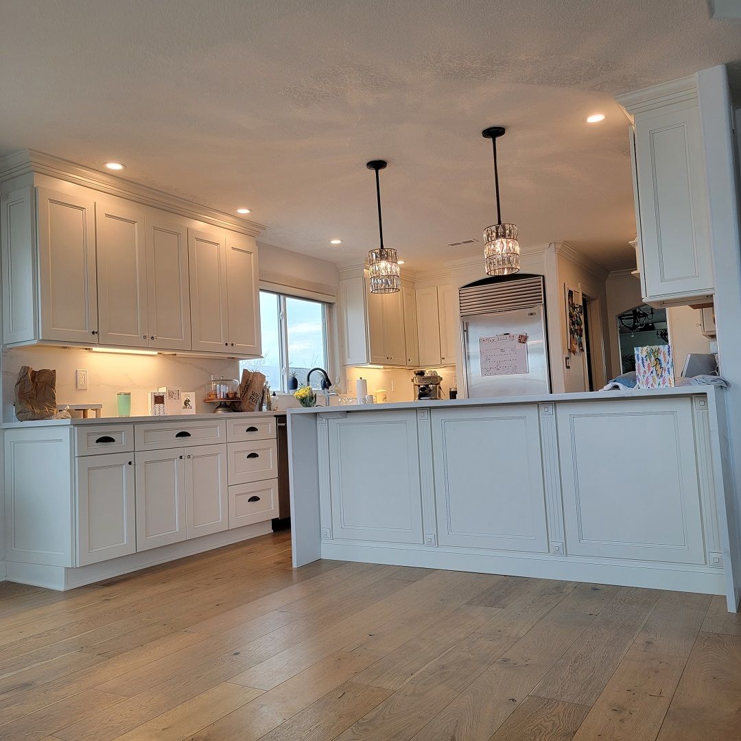 A kitchen with white cabinets, hardwood floors, and a large island