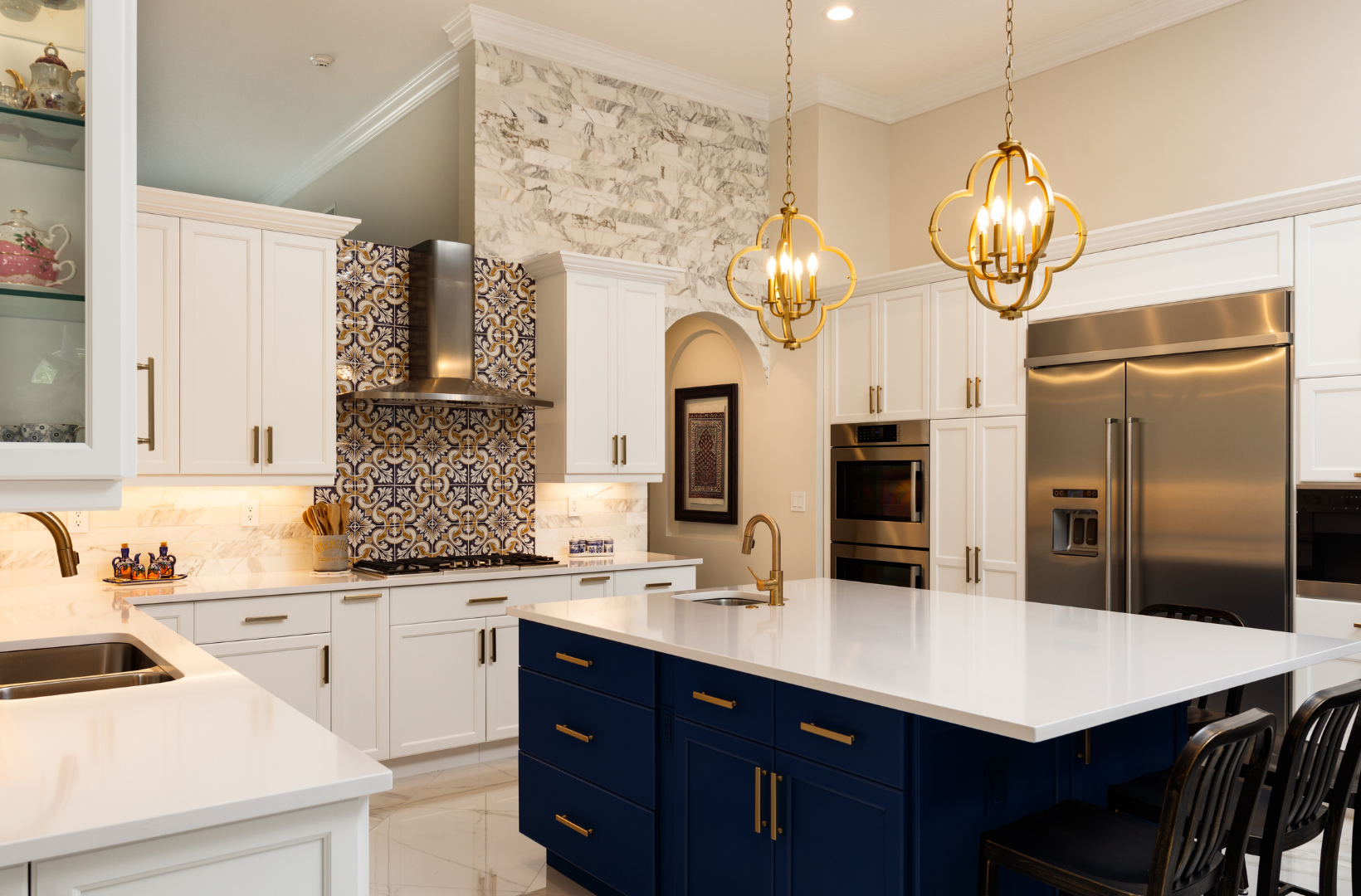 A kitchen with white cabinets, blue cabinets, stainless steel appliances, and a large island