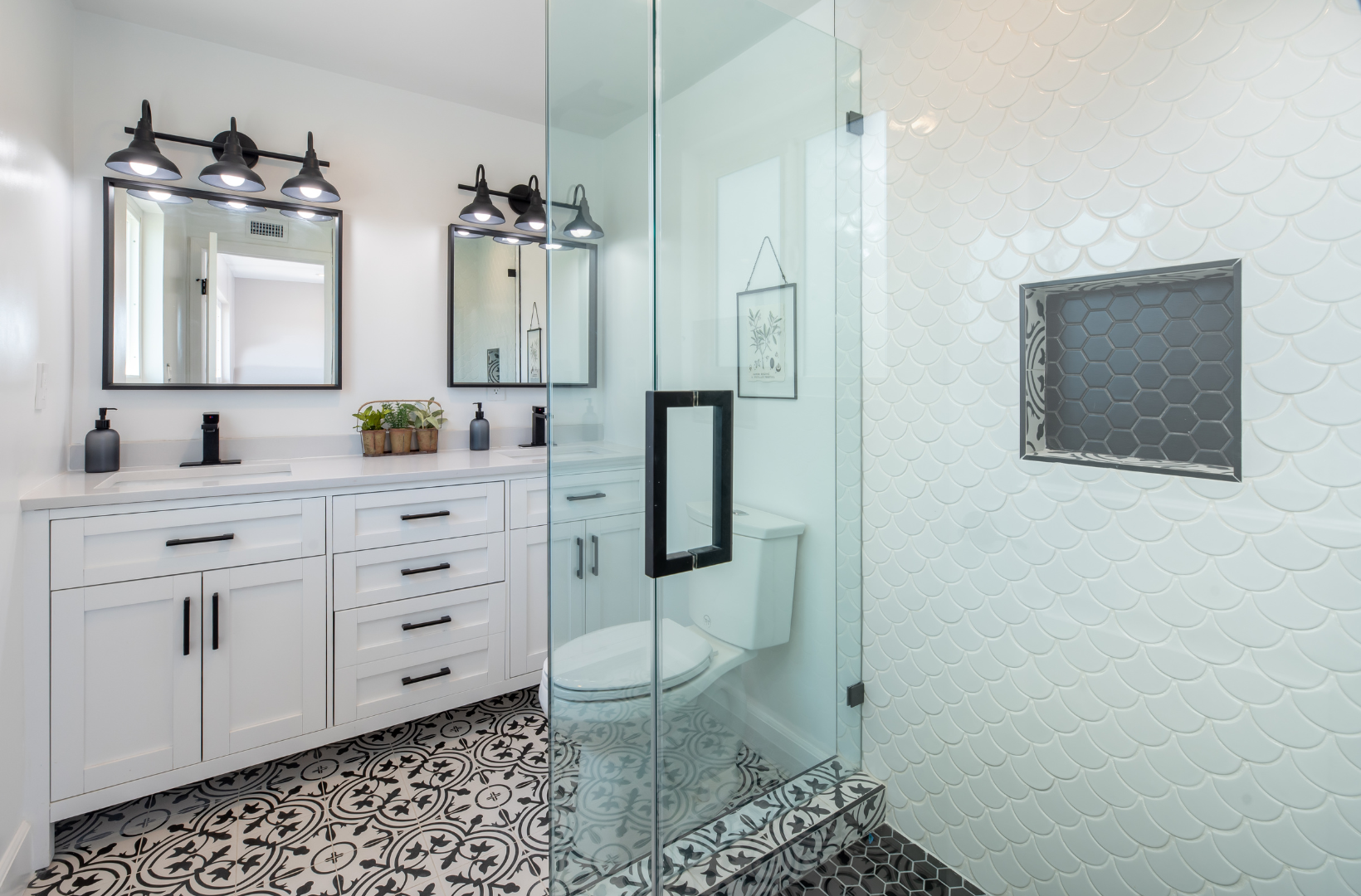 A bathroom with two sinks, a toilet, and a walk in shower