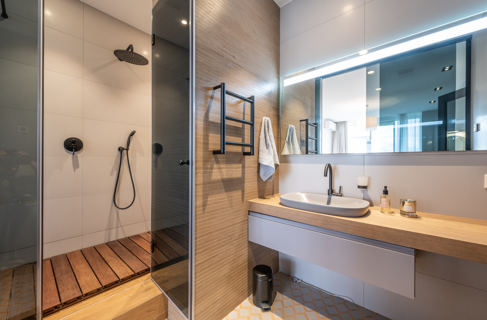 A bathroom with a sink, shower and mirror