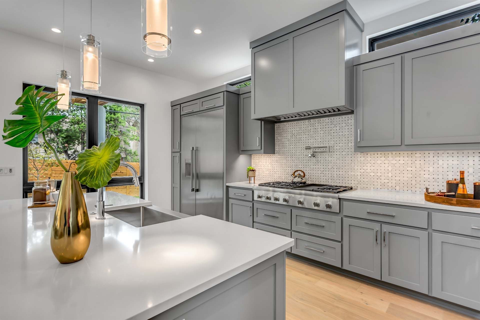 A kitchen with gray cabinets, white counter tops, and stainless steel appliances