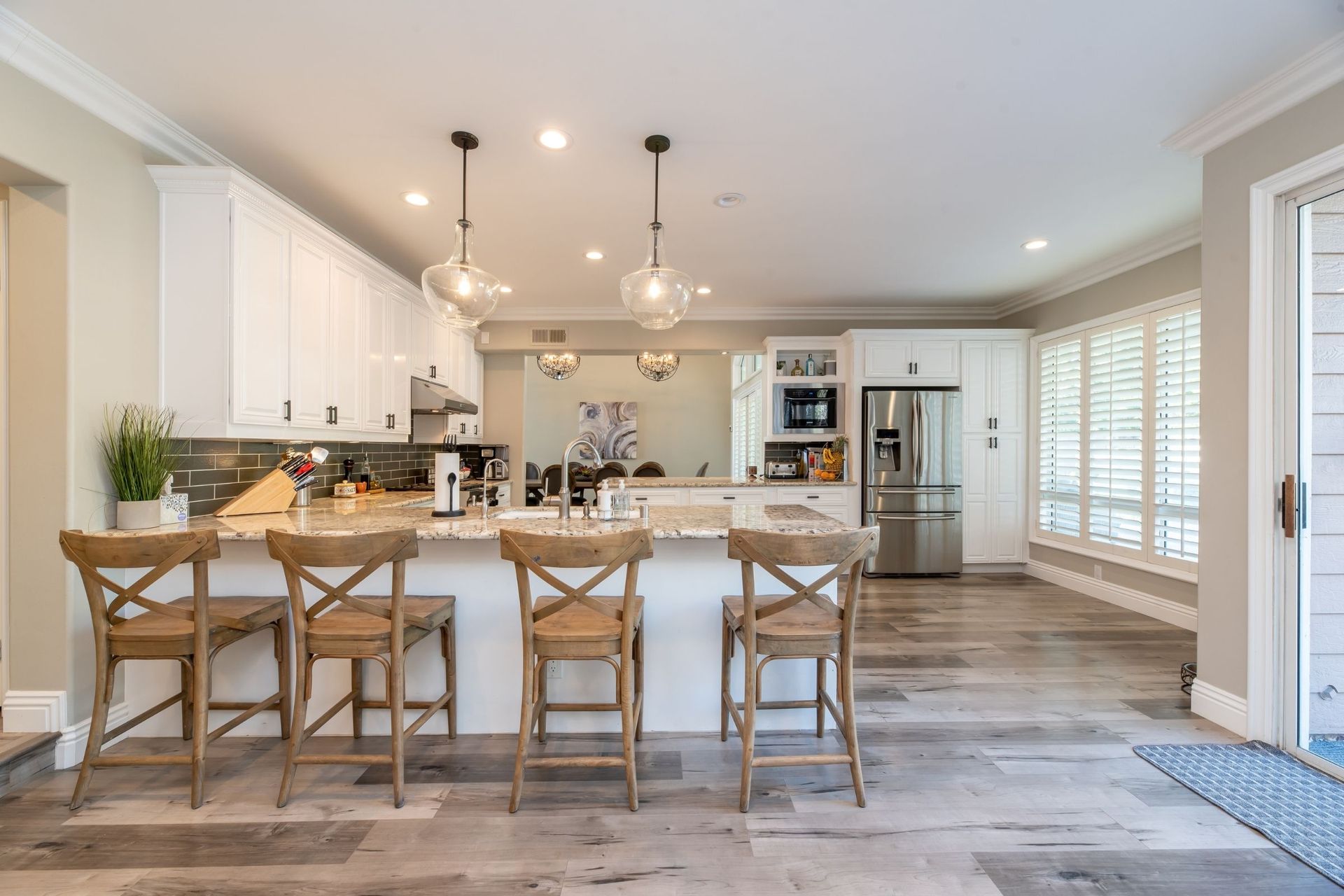 A kitchen with a large island, stools and a refrigerator