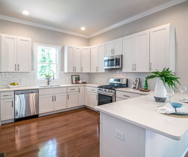 A kitchen with white cabinets, stainless steel appliances, and hardwood floors