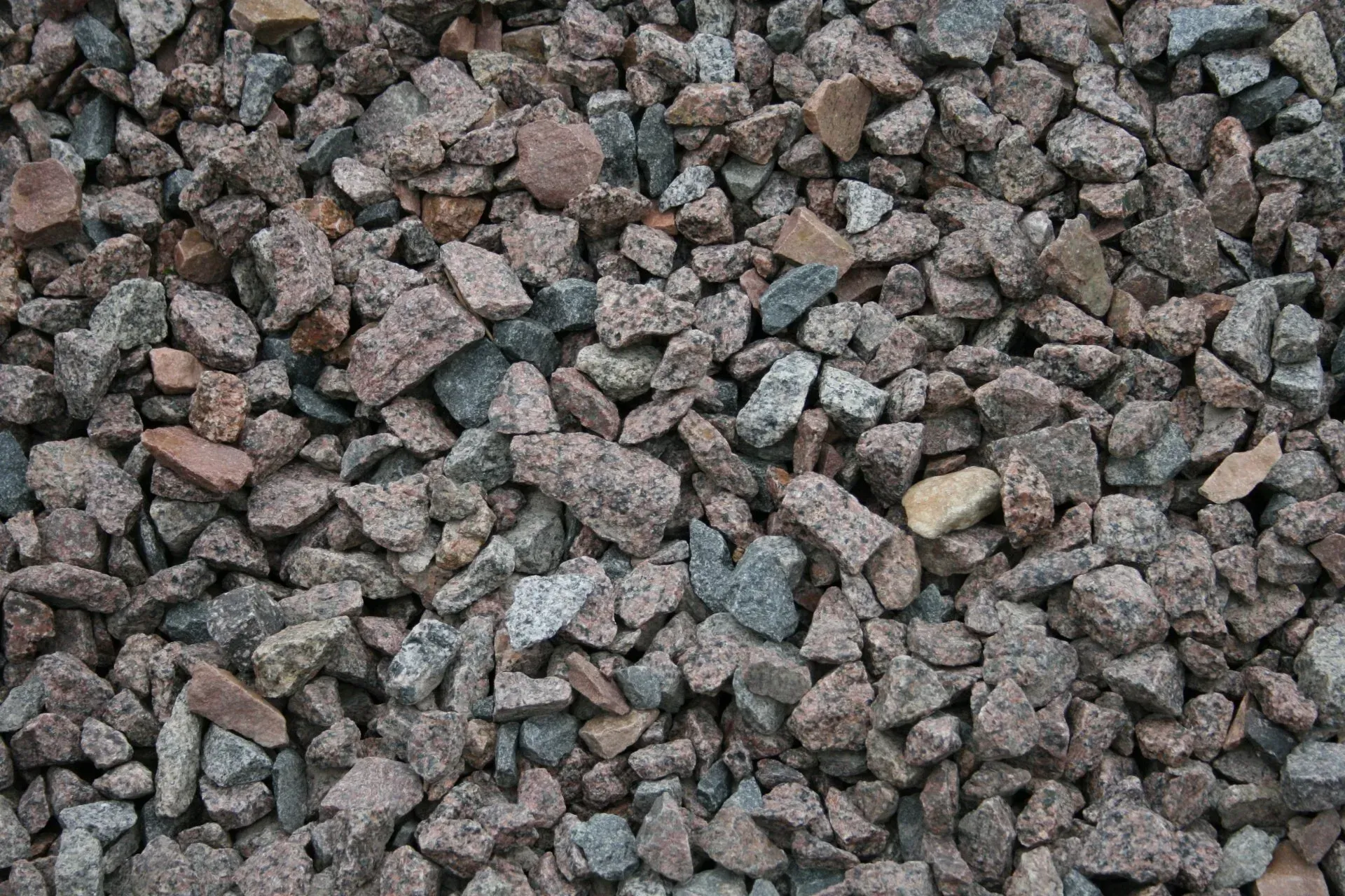A close-up view of crushed granite stones in shades of grey, pink, and tan.