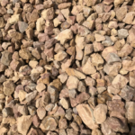 A close-up view of crushed tan and light brown landscape gravel, showing various stone sizes and angular textures.