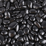A collection of smooth, polished black river stones tightly packed together.