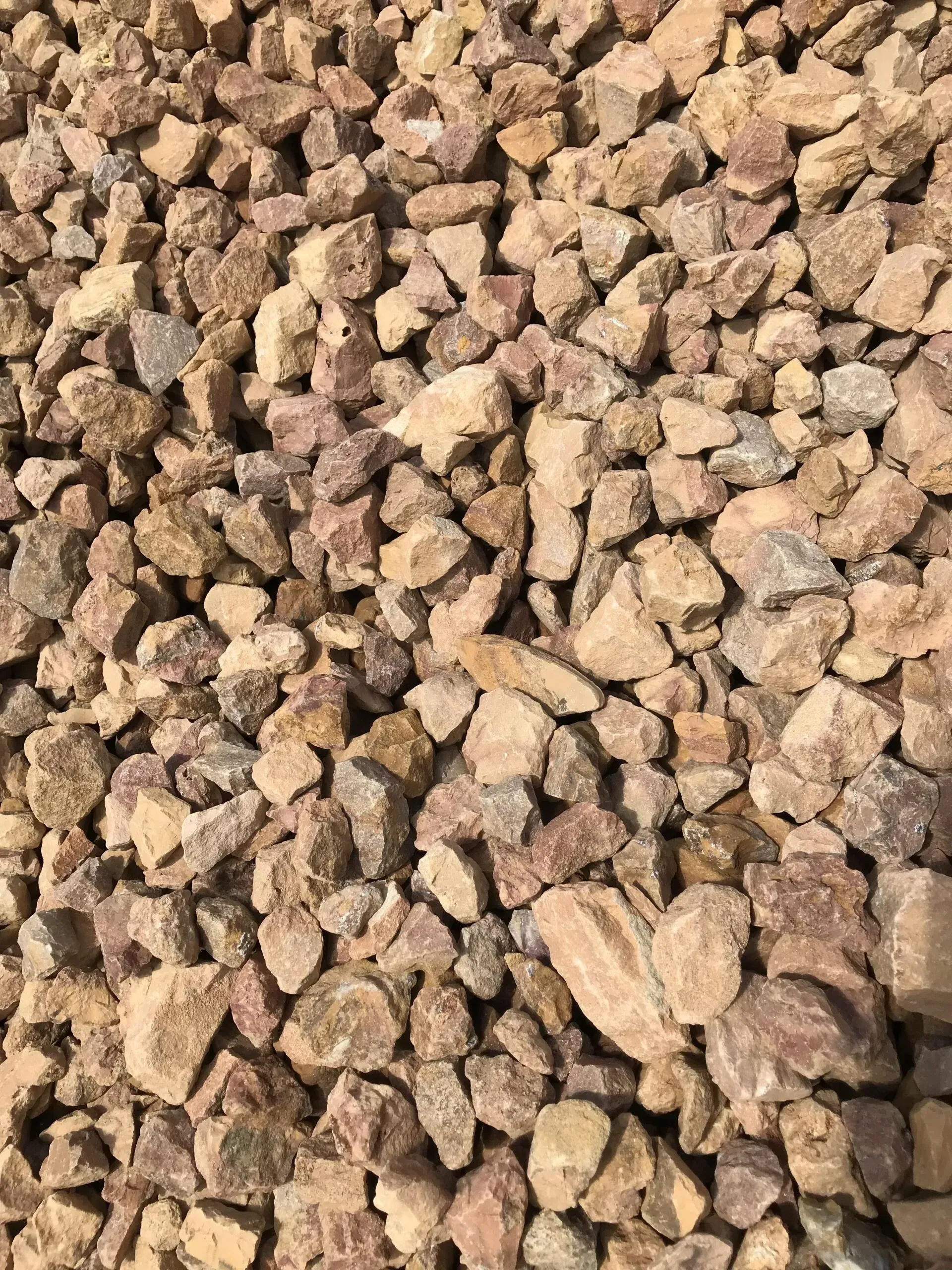 A pile of crushed, angular stones in various shades of beige, tan, and light brown.