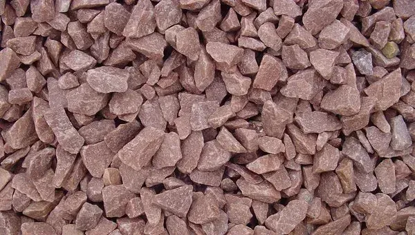 A close-up view of crushed red decorative landscape gravel.