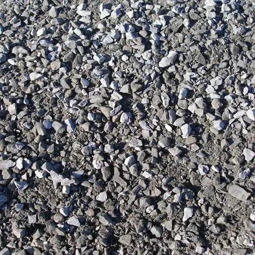A close-up view of crushed gray stone and gravel of varying sizes mixed with dirt.
