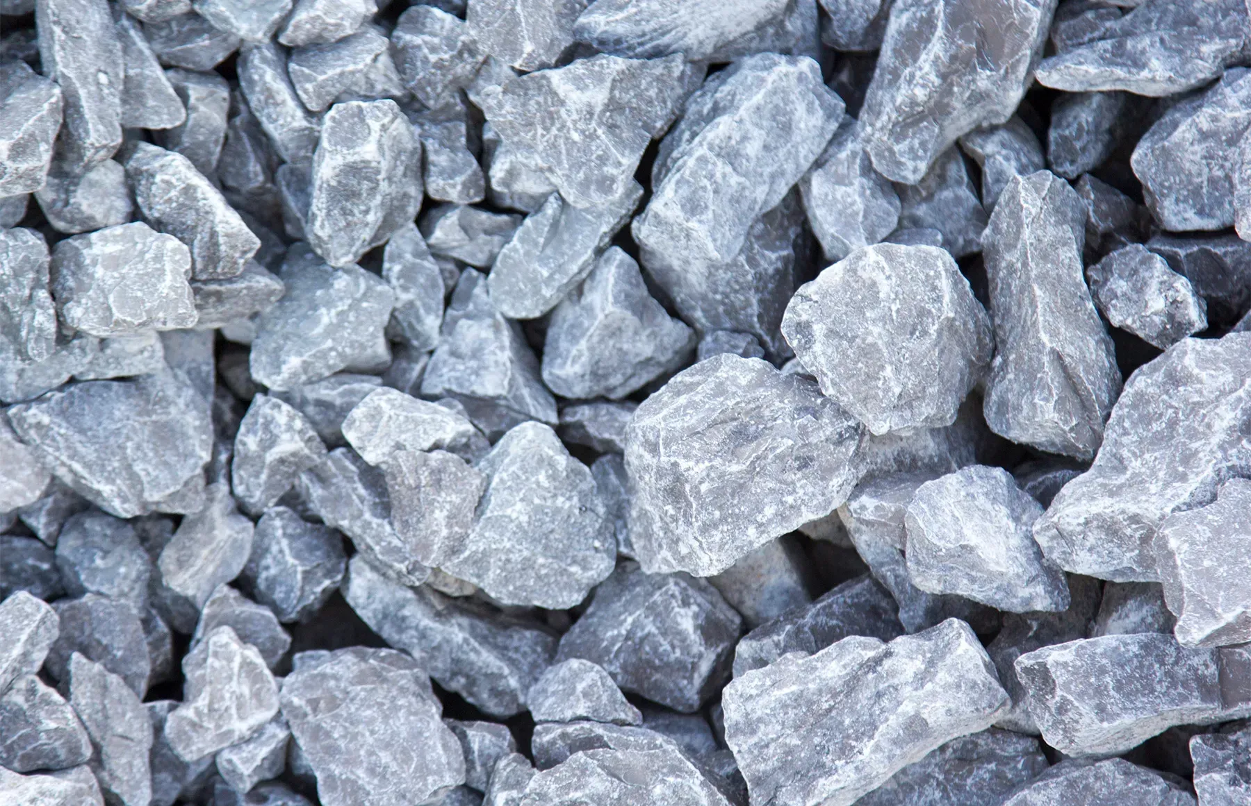 A close-up view of loose, angular grey crushed stone or gravel piled together.