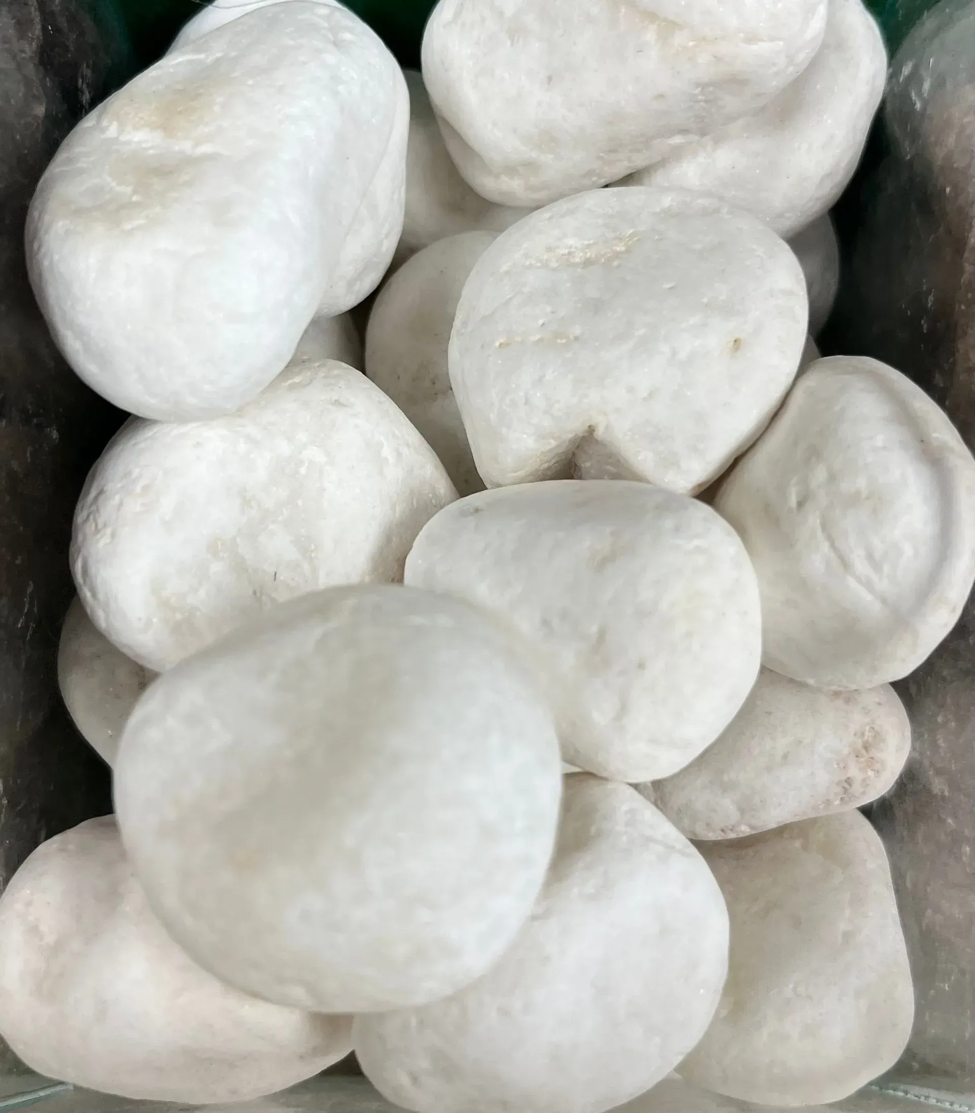 A collection of smooth, white decorative garden stones piled together.