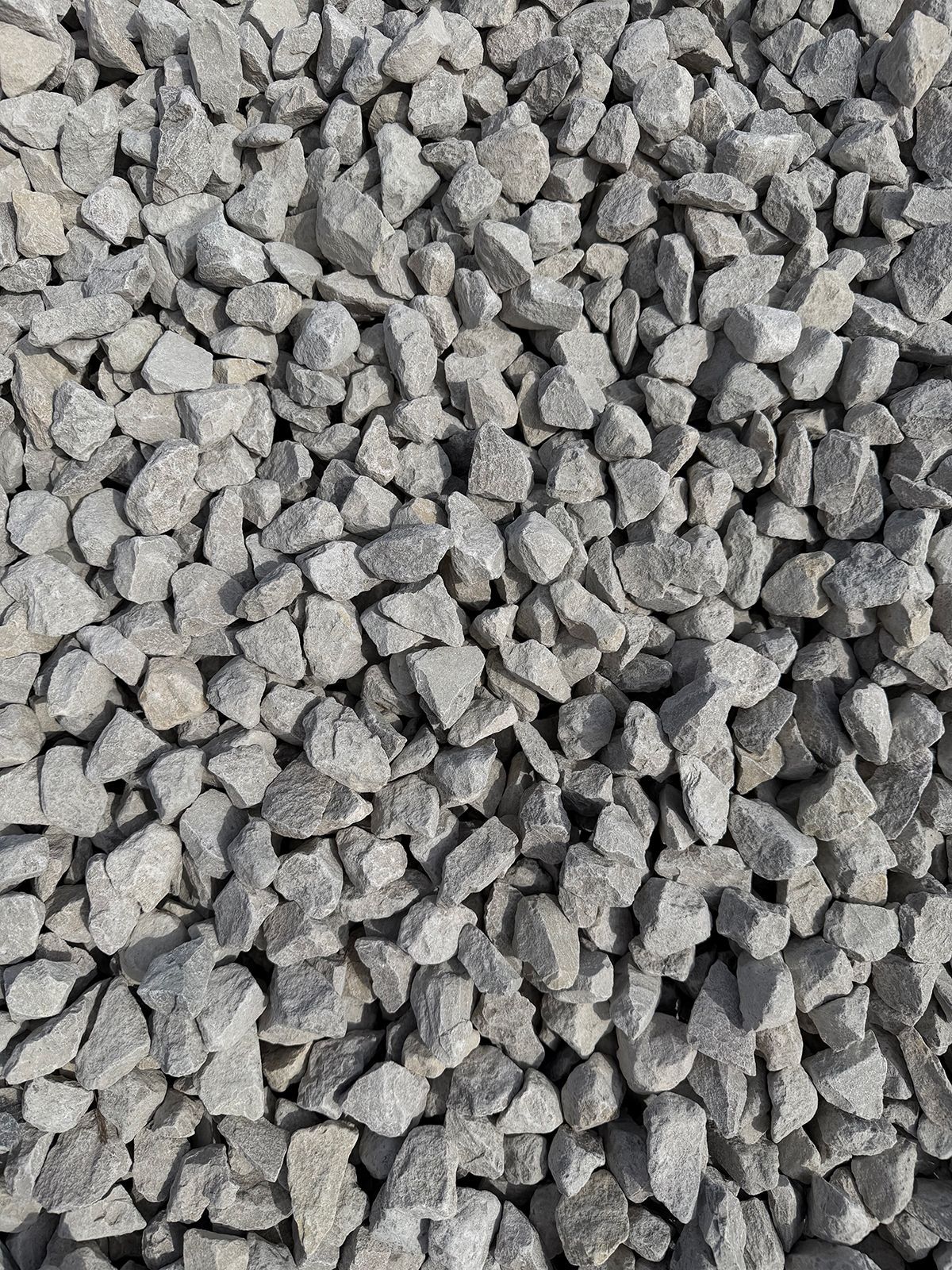 A close-up view of numerous angular, light gray crushed rocks or stones covering the frame.