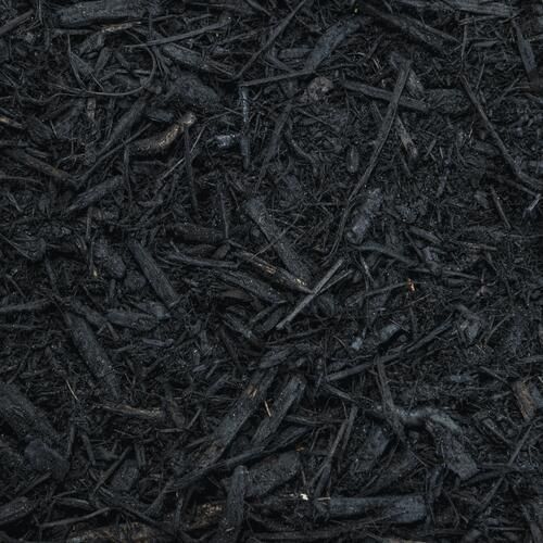 A close-up of dark, shredded black mulch pieces scattered in a dense, uniform layer.