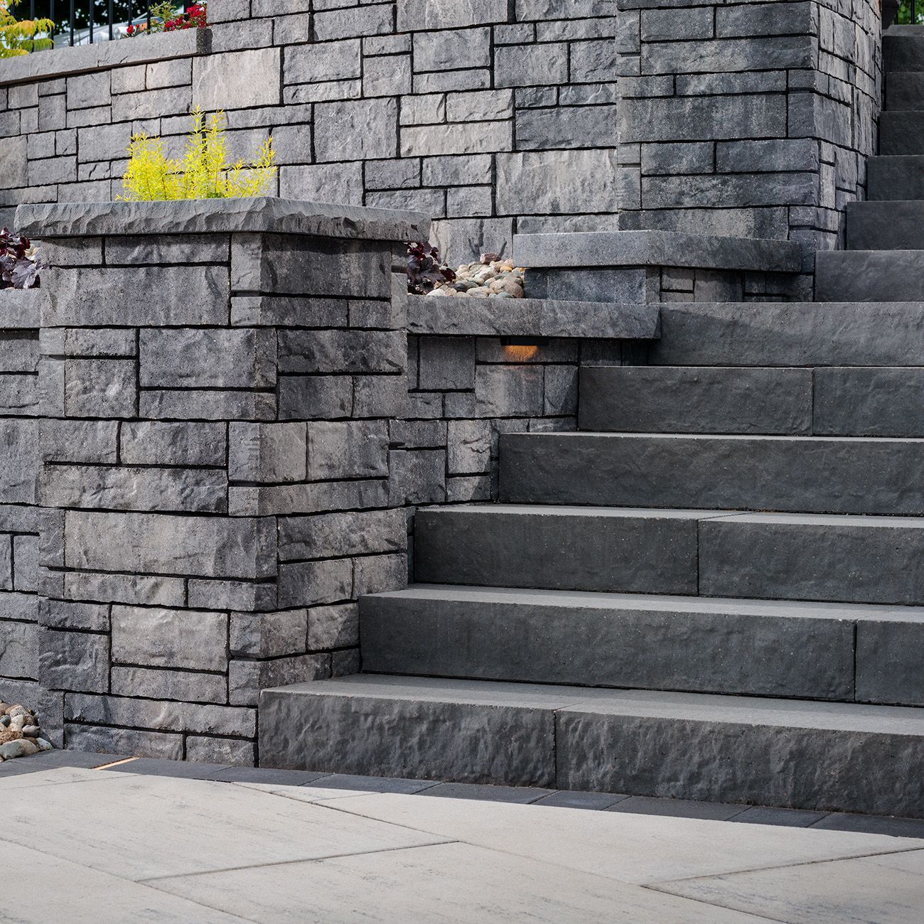 A stone staircase made of large, dark gray rectangular blocks next to a matching stone retaining wall.