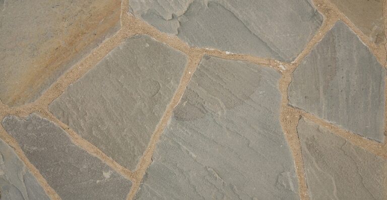 Flagstone patio with irregularly shaped gray stones and tan mortar joints.