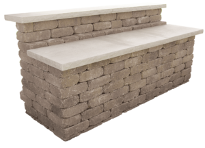 A two-tiered outdoor bar made of stacked tan stone blocks with smooth, light-colored concrete countertops.