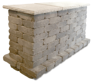 A rectangular outdoor counter built from stacked grey stone blocks with a flat, light-colored stone countertop.