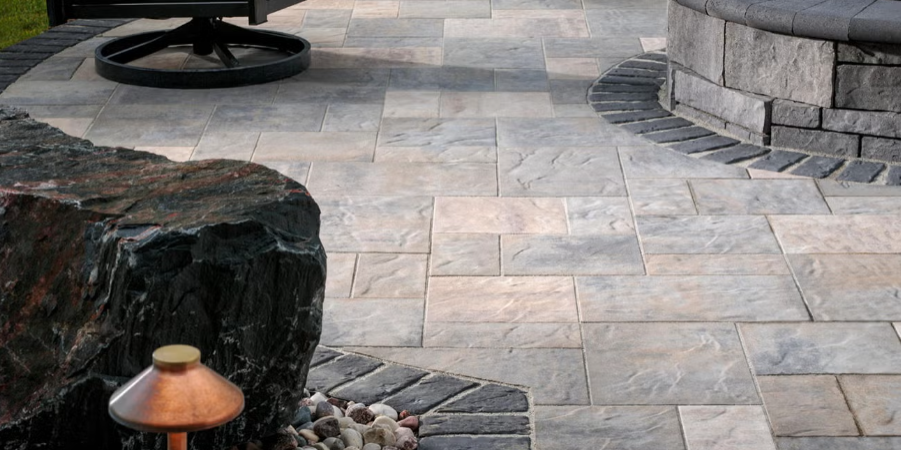 Stone patio with curved retaining wall, large rocks, and a lantern in the foreground