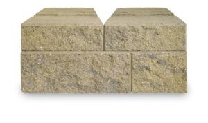 Two layers of rectangular, tan-colored textured concrete retaining wall blocks stacked in an alternating bond pattern.
