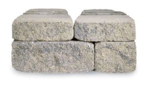 Four grey, rectangular stone landscaping blocks stacked in two layers with a rough, textured face.