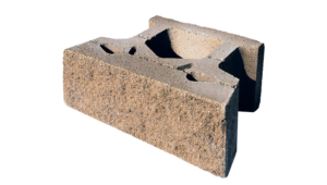 A tan, textured concrete landscaping retaining wall block with a hollow core, viewed from a high angle.