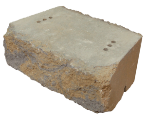 A single, rectangular, textured landscaping stone with a tan and grey rough-hewn face and two sets of drill holes on top.
